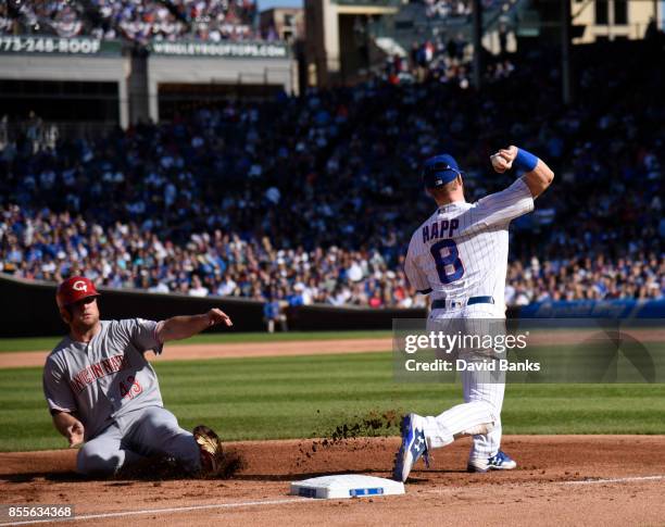 Ian Happ of the Chicago Cubs forces out Scott Schebler of the Cincinnati Reds at third base and throw to first base to complete a double play during...