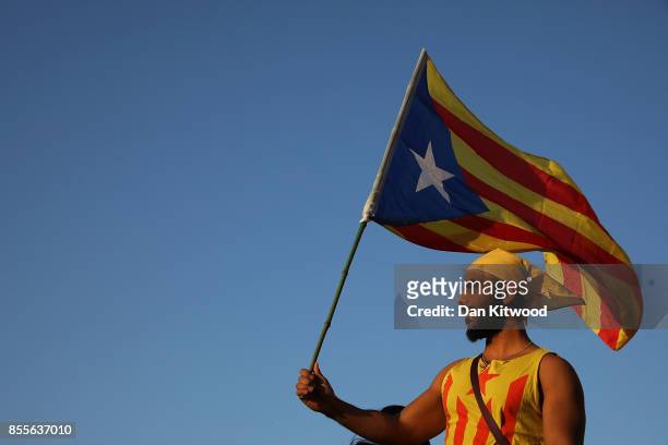 Man holds up a Catalan flag as people gather at the final pro-independence rally at Plaza Espana ahead of Sunday's referendum vote on September 29,...