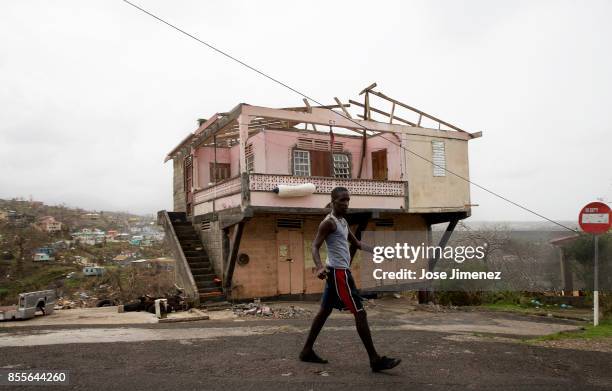 Man walks past a damaged house in Marigot, Dominica on September 28, 2017. Hurricane Maria inflicted catastrophic damages and at least 15 deaths in...