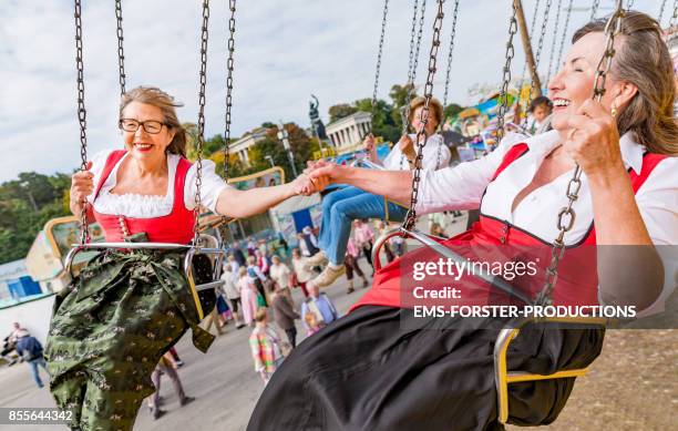 two active senior women in traditional bavarian dirndl dresses having great fun visiting the beer fest 2017 in munich. - oktoberfest stock pictures, royalty-free photos & images