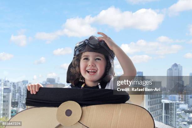 little girl flying a cardboard airplane above city - 飛機師帽 個照片及圖片檔