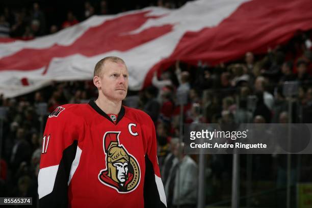 Daniel Alfredsson of the Ottawa Senators stands during the singing of the national anthems as a large Canadian flag passes through the crowd prior to...