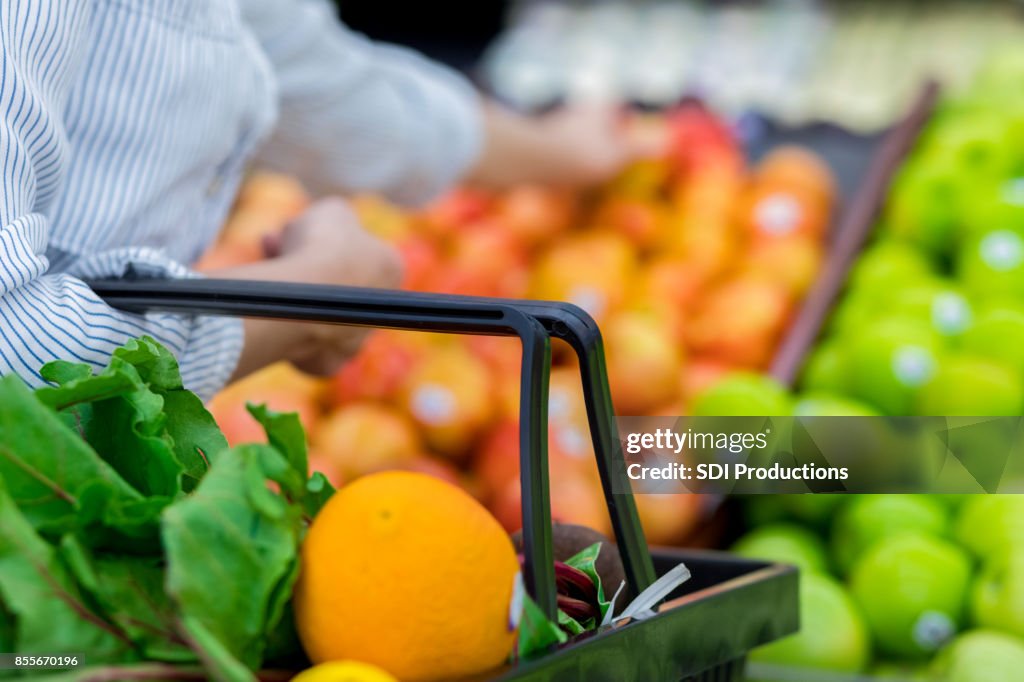 Unrecognizable grocery store customer reaches for fresh produce
