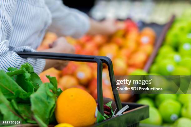unrecognizable grocery store customer reaches for fresh produce - shopping basket stock pictures, royalty-free photos & images
