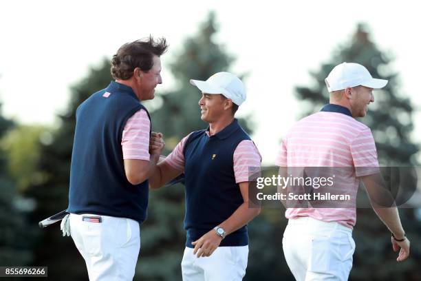 Phil Mickelson of the U.S. Team and teammate Rickie Fowler shake hands as Daniel Berger walks off during the second round of the Presidents Cup at...