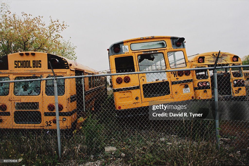 Old school buses behind a fence