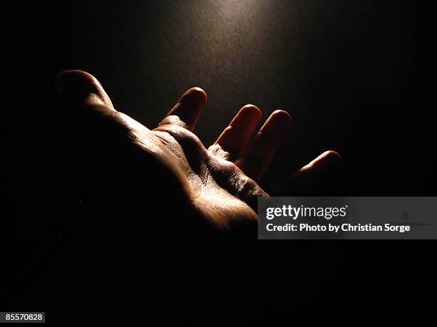 hand lit by a single light - 祈る 手 ストックフォトと画像