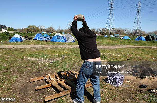 Keith Day uses a rock to break up a pallet for firewood at a homeless tent city March 23, 2009 in Sacramento, California. Sacramento mayor Kevin...