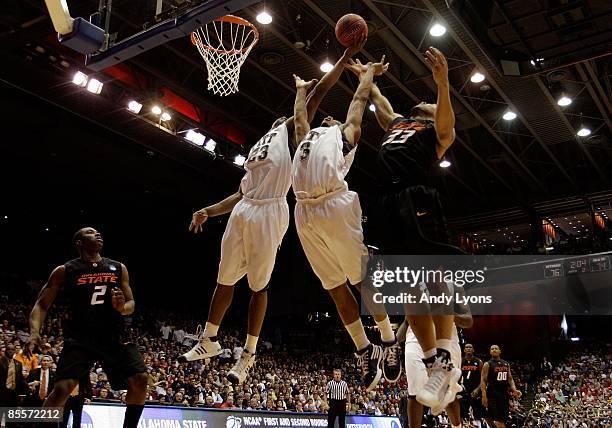 Sam Young and Jermaine Dixon of the Pittsburgh Panthers go up for a rebound against Marshall Moses of the Oklahoma State Cowboys during the second...