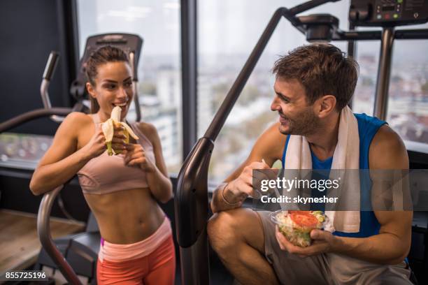 happy athletic couple eating healthy food on a break in a gym. - food competition stock pictures, royalty-free photos & images