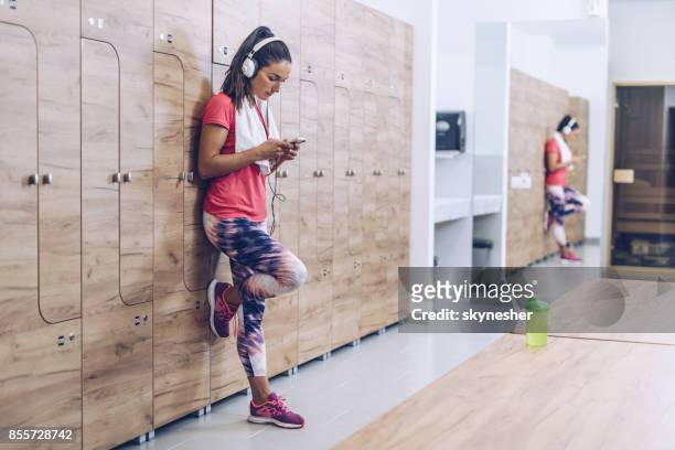 全長運動女性ジムのロッカー ルームで音楽を聴くこと。 - locker room ストックフォトと画像