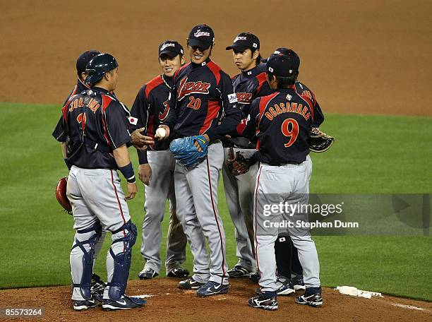 Starting pitcher Hisashi Iwakuma of Japan smiles on the mound surrounded by teammates as he is relieved in the eighth inning against Korea during the...