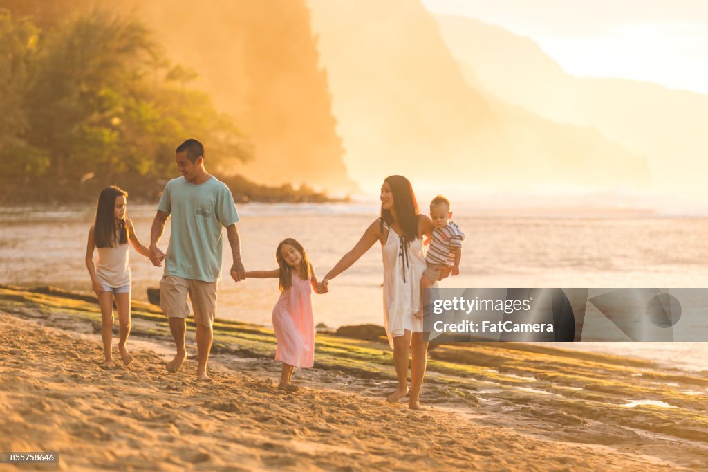 Hawaiian famille marche sur la plage au coucher du soleil