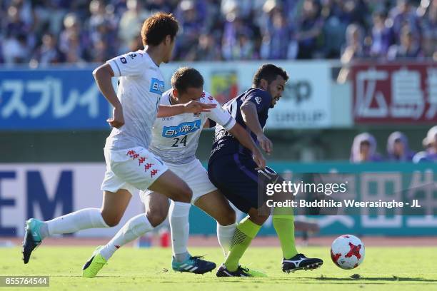 Felipe Silva of Sanfrecce Hiroshima controls the ball under pressure of Akito Fukumori and Hiroki Miyazawa of Consadole Sapporo during the J.League...