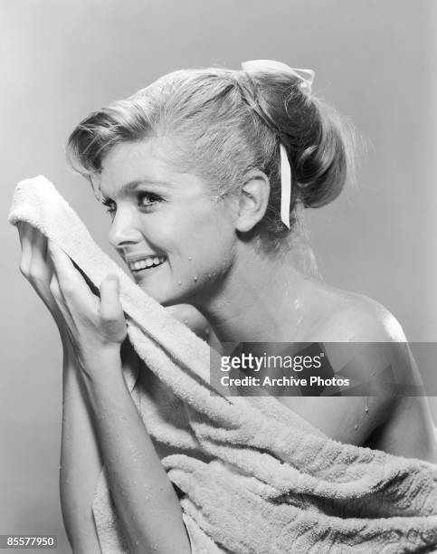 Young woman dries her face with a towel, circa 1950.