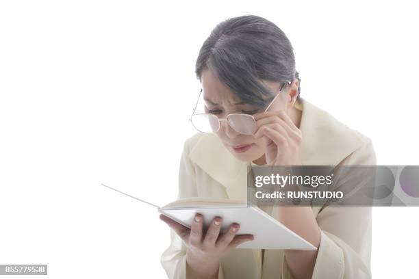 mature woman with eye glasses trying to read book - eyesight problem stock pictures, royalty-free photos & images