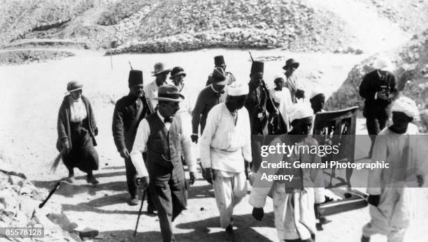 Carved cedar wood chair is carried away from the Tomb of Tutankhamun in the Valley of the Kings by Egyptian labourers, escorted by archaeologist...