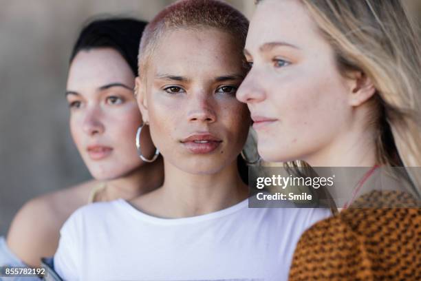 three beautiful young women looking various directions - grupo de mujeres fotografías e imágenes de stock