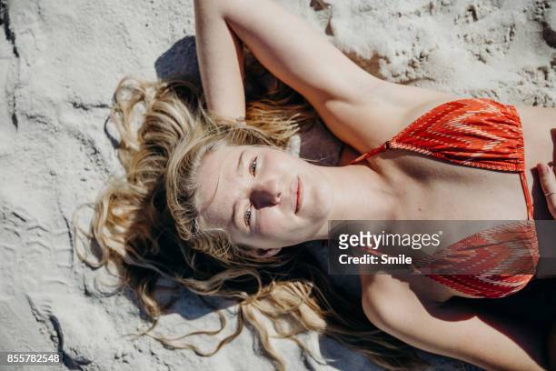 portrait of young woman lying on the beach - smile woman stock-fotos und bilder