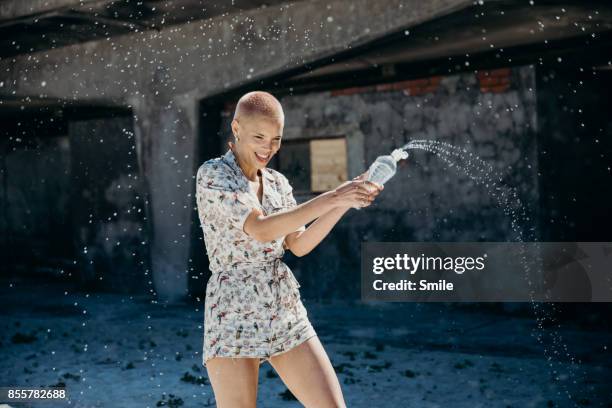 young woman spraying water from bottle - one person smile outdoors stock-fotos und bilder