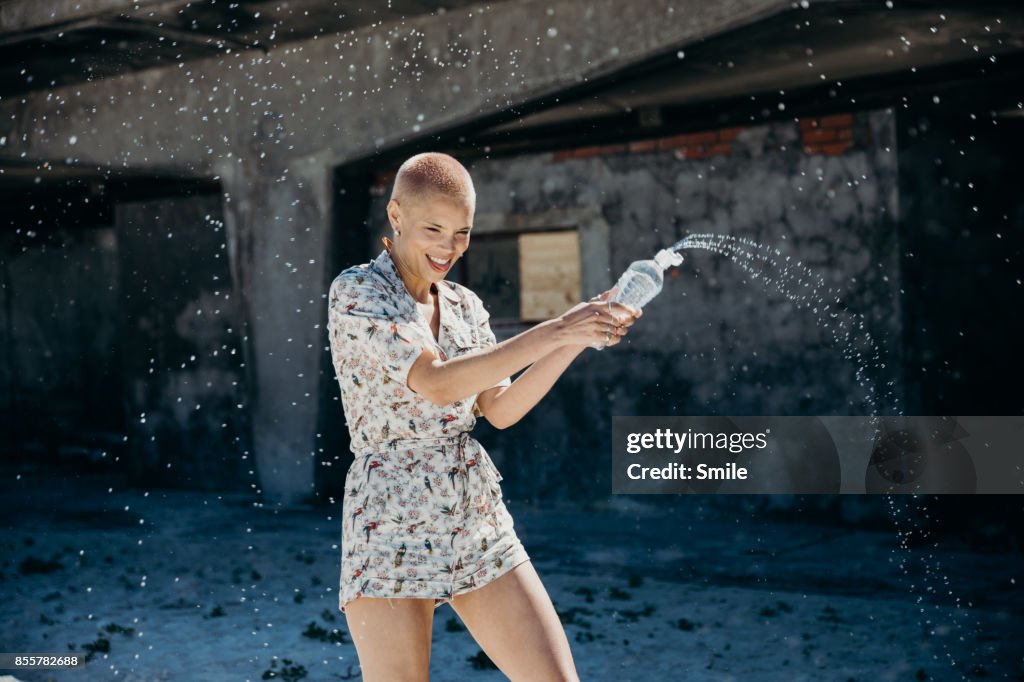 Young woman spraying water from bottle
