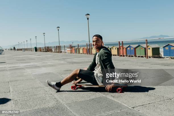 Portrait of a man sitting on a skateboard smiling