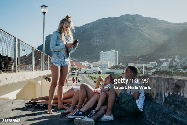 Young woman reads mobile phone to group of friends