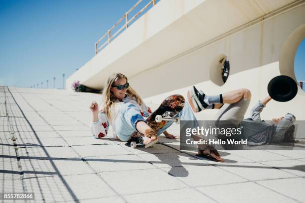 young couple fallen off skateboard - play off stock pictures, royalty-free photos & images