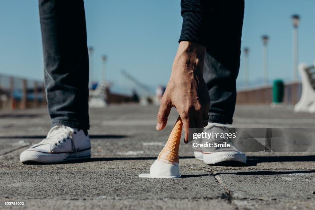 Man reaching for a dropped ice-cream on the boardwalk