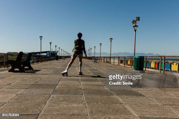 women roller skating on the boardwalk, from behind - one person smile outdoors stock-fotos und bilder
