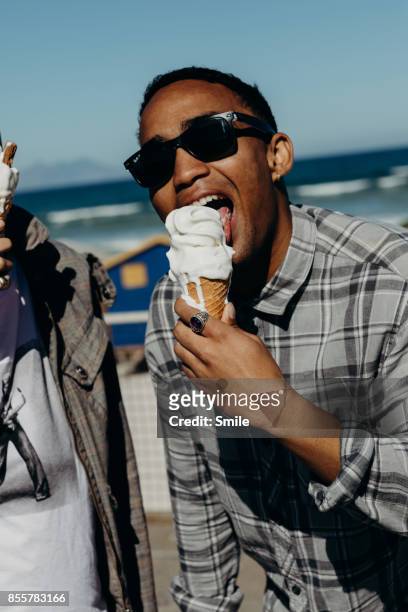 young man with sunglasses licking an ice-cream - african travel smile foto e immagini stock