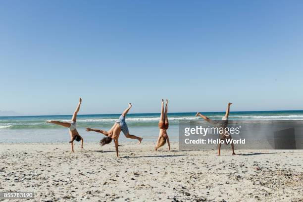 friends doing hand stands on  the beach - handstand beach stock pictures, royalty-free photos & images
