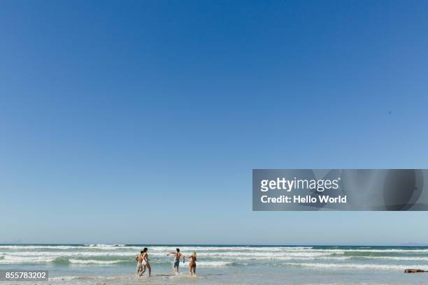 friends running in the waves. wide shot - clear sky stock-fotos und bilder