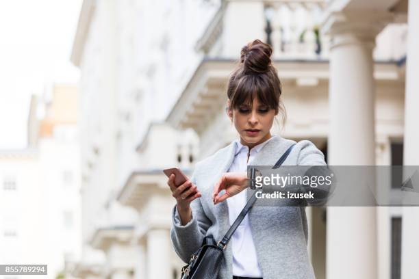 besorgt frau mit smartphone vor stadthaus - business women london stock-fotos und bilder