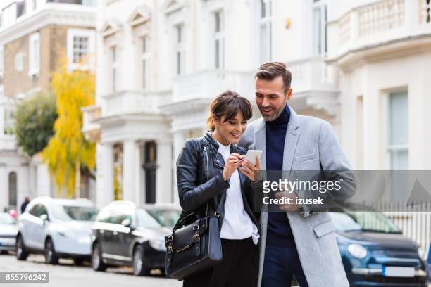 erwachsenes paar mit smartphone zusammen in der stadtstraße - ehemann stock-fotos und bilder