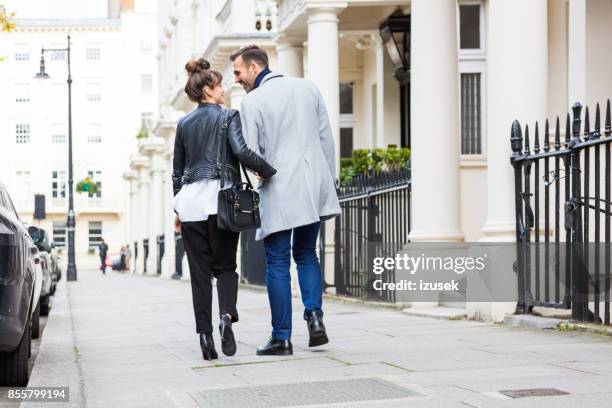 back view of happy elegant couple walking in the city street - back of leather jacket stock pictures, royalty-free photos & images