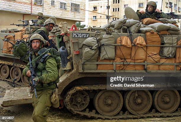 An Israeli soldier stands guard while his unit prepares to defend itself against Palestinian snipers as they hold a position January 21, 2002 in a...