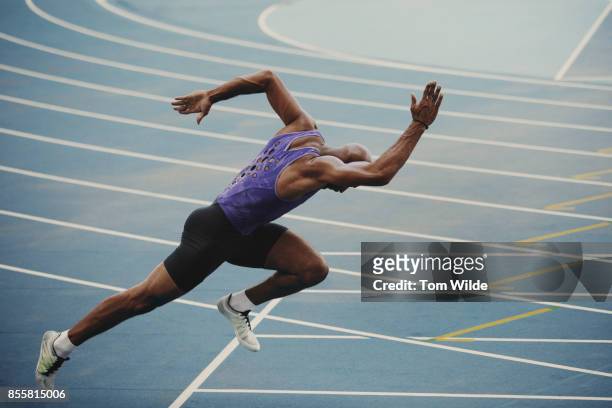 male athlete pushing out of the starting blocks as he starts his sprint race - sprint photos et images de collection