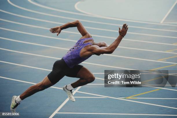 male athlete pushing out of the starting blocks as he starts his sprint race - corrida-de-velocidade - fotografias e filmes do acervo