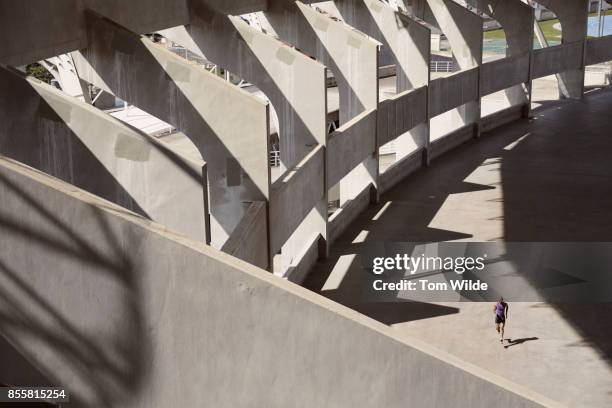 long shot of a male athlete as he runs through a concrete stadium - center athlete stock pictures, royalty-free photos & images