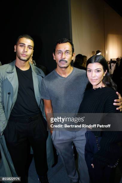 Stylist Haider Ackermann standing between Kourtney Kardashian and her companion Younes Bendjima pose Backstage after the Haider Ackermann show as...