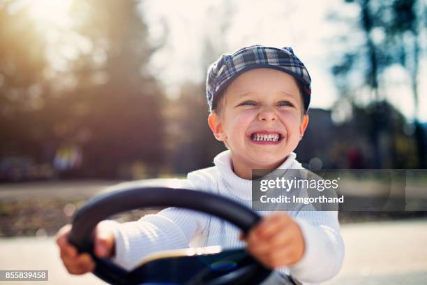 happy little boy driving small car in the park - toy car stock pictures, royalty-free photos & images