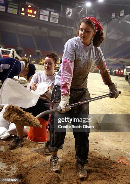 Alexa Westbee and Beka Marcis, students from Concordia College, fill sandbags during a sandbagging operation at the Fargo Dome March 24, 2009 in...