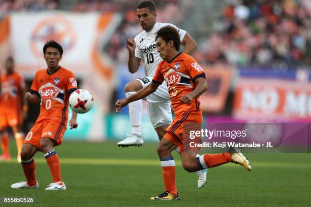 Masaru Kato of Albirex Niigata controls the ball under pressure of Lukas Podolski of Vissel Kobe during the J.League J1 match between Albirex Niigata...