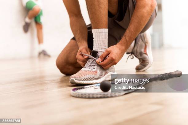 squashspieler, die schnürsenkel zu binden - squash racquet stock-fotos und bilder