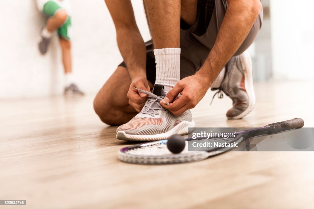 Squash player tying shoelaces