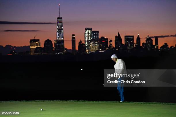 Adam Scott of Australia and the International Team chip on the practice range early during the third round of the Presidents Cup at Liberty National...