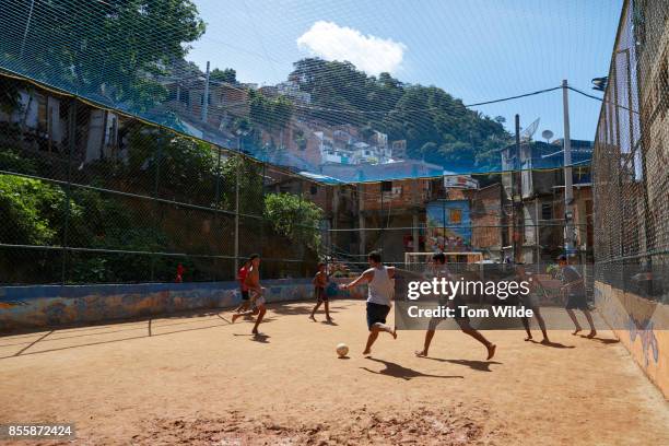 group of young men playing football on a dirt court in rio - brazilian playing football fotografías e imágenes de stock