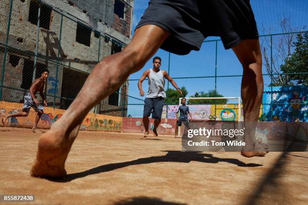 group of men playing football on a dirt court in rio de janeiro - brazilian playing football fotografías e imágenes de stock