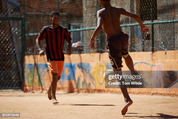 two young men playing football on a dirt court - barefoot teen boys stock pictures, royalty-free photos & images